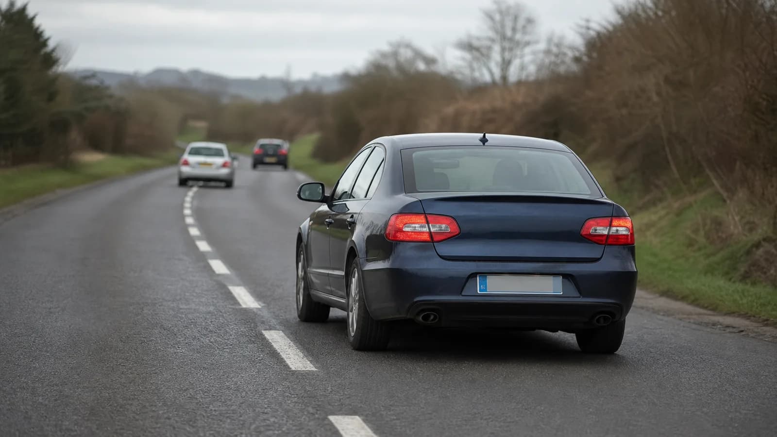 Berline banalisée bleu nuit circulant parmi d’autres véhicules sur une route française